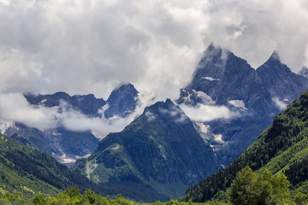 Peak of the mountain with glaciers against clouds and sky. Caucasian ridge, Russia.