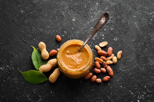 Peanut butter and nuts on a black stone background Healthy food Top view