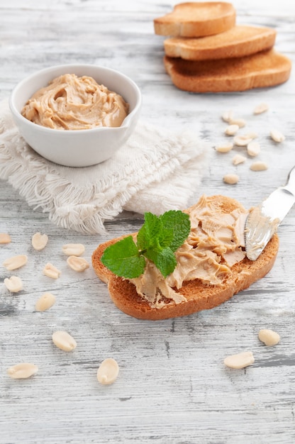 Peanut Butter Sandwich. Decorated with mint. In the background is a cup with peanut butter and bread.