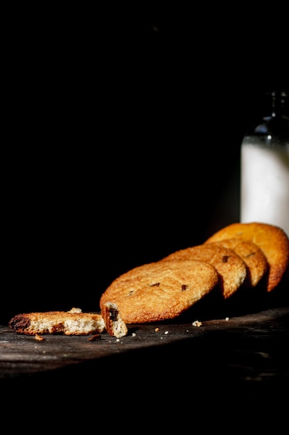 Peanut cookies and a bottle of milk on a dark background