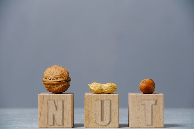 Peanut hazelnut and walnut are laid out on wooden cubes gray backgroundVitamins and healthy food