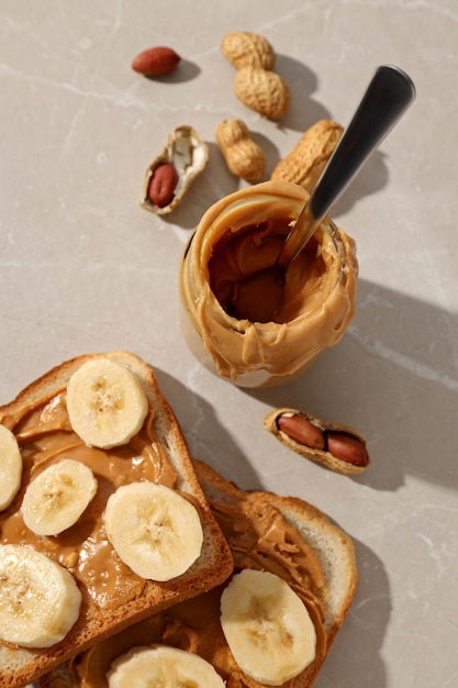 Peanut paste in a glass jar with toast on a light background