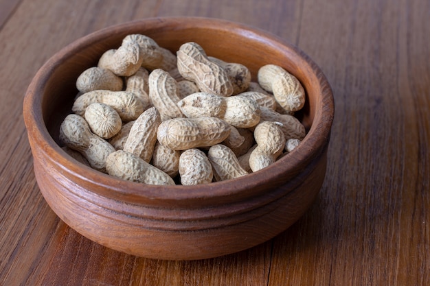 Peanuts in the bowl on the wood background