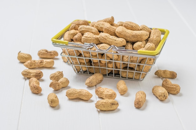 Peanuts in a grocery basket on a white wooden table