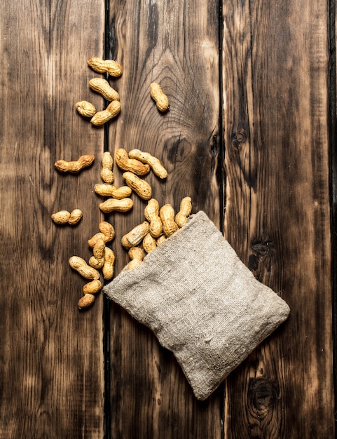 Peanuts in the old bag. On wooden background.