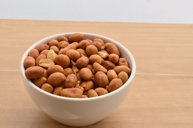 Peanuts in shell in white bowl on wooden table. Traditional peanut from Brazil.