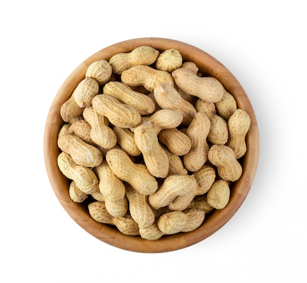 Peanuts in wood bowl on white wall. 