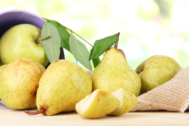 Pears in bucket on burlap on wooden table on nature background