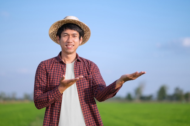 A peasant man wearing a woven hat is standing in a field posing with his hands up. Selective Focus on face image.