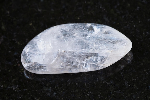 Pebble of Natrolite gemstone on dark background