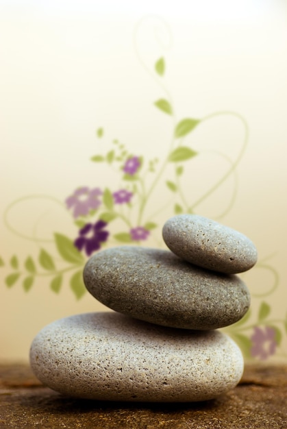 Pebbles pyramid on a rock with floral design at the background  beige background