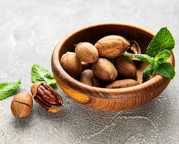 Pecan nuts in bowl on a grey concrete background