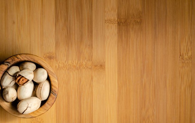 Pecans in a shell in a plate on a wooden background.