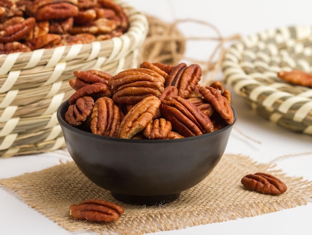 Pecanut served in a bowl isolated on napkin side view of nuts on grey background