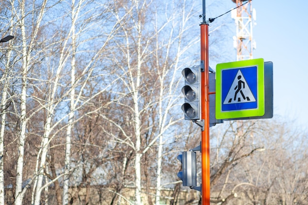 A pedestrian crossing sign with a reflective coating and a traffic light is installed on the street