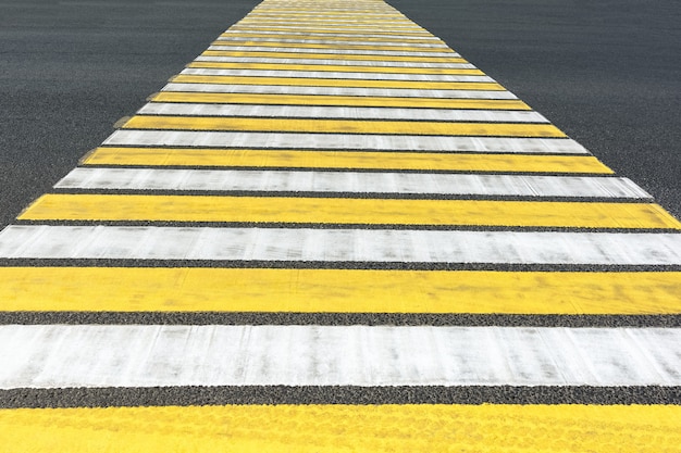 Photo pedestrian crosswalk with yellow and white stripes marking of the intersection of the roadway