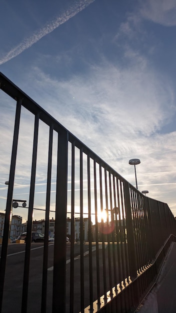 A pedestrian looks through vertical bars at the sun that sets below the horizon in southwestern Eur