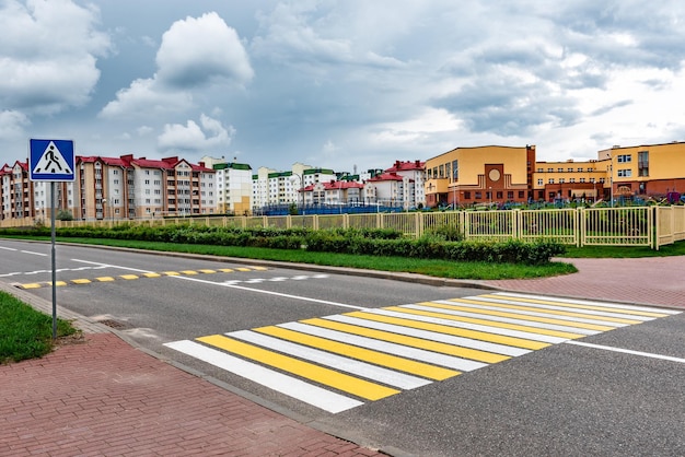 Pedestrian (zebra) crossing on empty city street near school building.