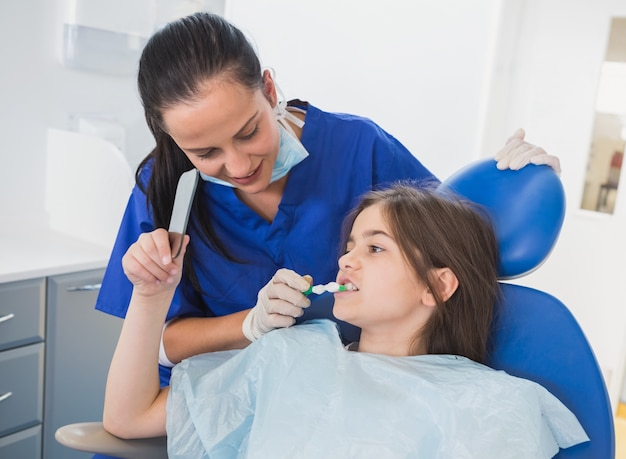 Pediatric dentist brushing teeth to her young patient 