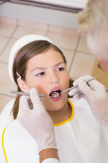 Pediatric dentist examining a patients teeth in the dentists chair