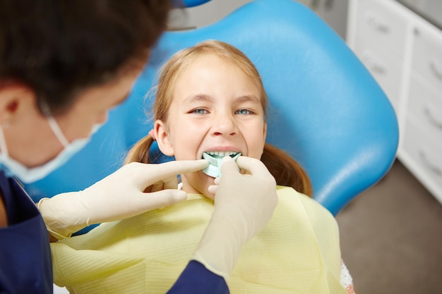 Pediatric dentist tries on the little girl a mouth guard for identifying and correcting the bite