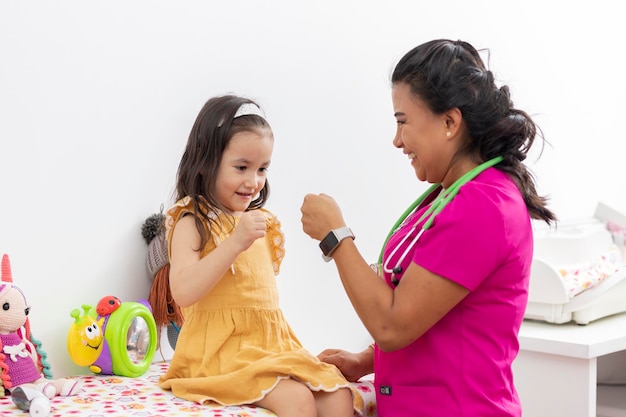 Pediatric doctor shakes hands with a little girl who is examining her in her office