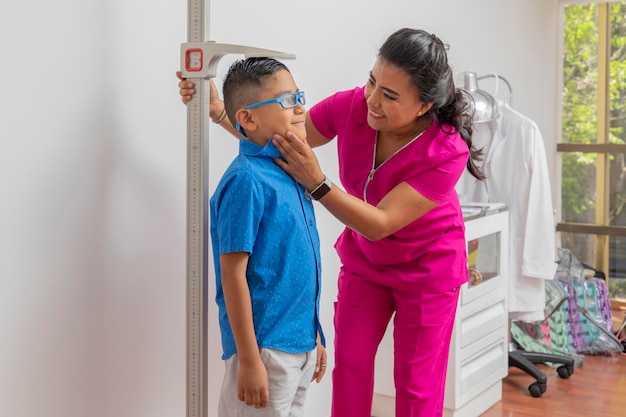 Pediatric female doctor holding a child's head while measuring it with a floor ruler