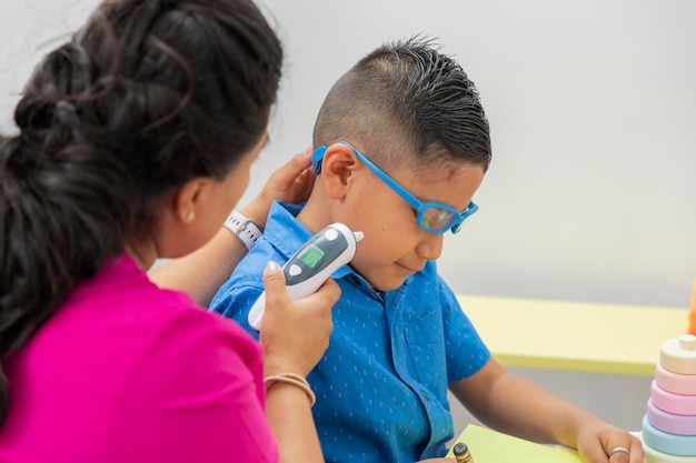 Pediatrician checking the temperature of a child with glasses in his office