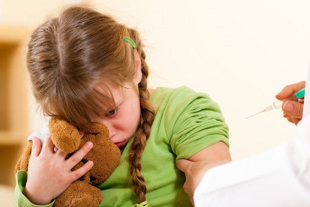 Pediatrician doctor applying syringe to child