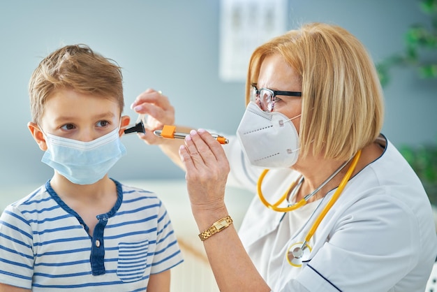 Pediatrician doctor examining little kids in clinic ears check. High quality photo