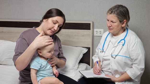 Pediatrician does checkup of baby sitting on mother lap