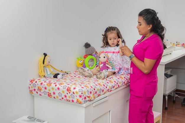 Pediatrician finishing checking a girl's ear in his office with copy space