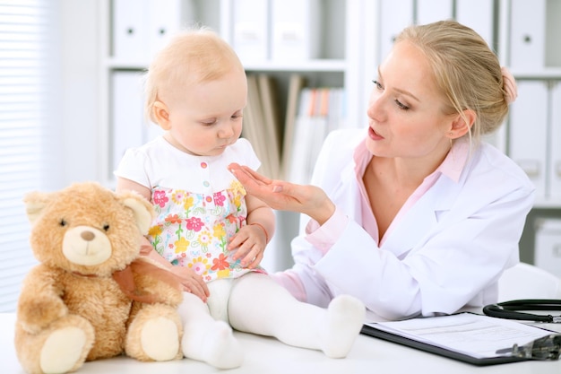 Photo pediatrician is taking care of baby in hospital little girl is being examine by doctor with stethoscope health care insurance and help concept