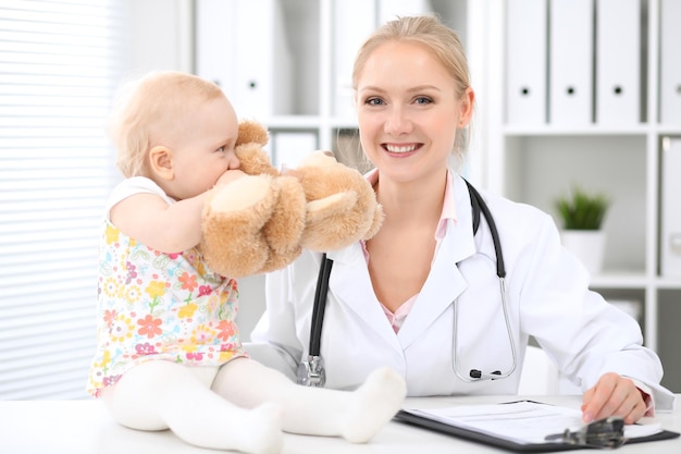 Pediatrician is taking care of baby in hospital. Little girl is being examine by doctor with stethoscope. Health care, insurance and help concept.