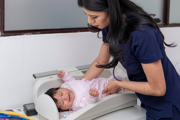 Pediatrician laying a baby on the scale in her office for weighing