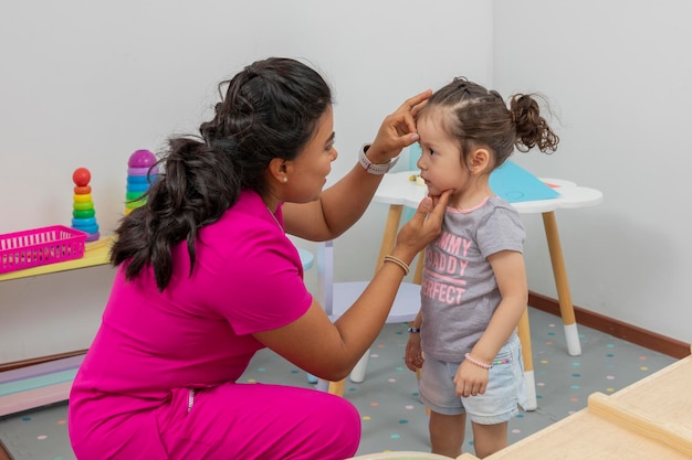 Pediatrician rewards a girl who is in his office placing a star of good conduct on her forehead