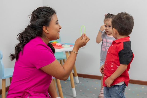 Pediatrician showing a bracelet to some children who are playing in his office