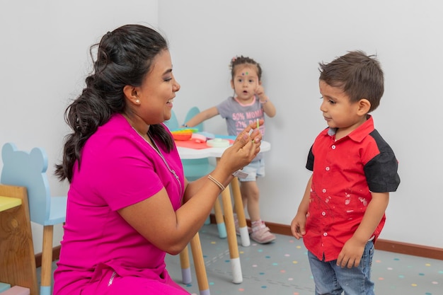 Pediatrician showing a child a bracelet and a girl in the background raises her hand because she also wants one