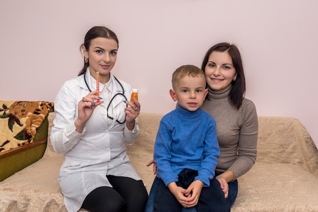 Pediatrician with medicament and boy patient with his mom