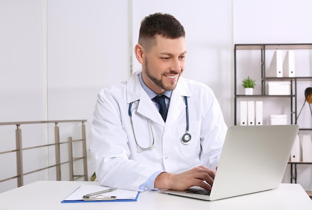 Pediatrician working on laptop at desk in office