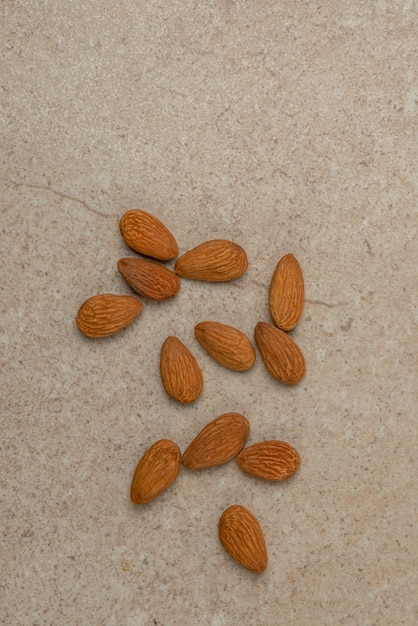 Photo peeled almonds. nut background, vertical photo, almonds in top view in a saucer and scattered around. place to insert text or design.