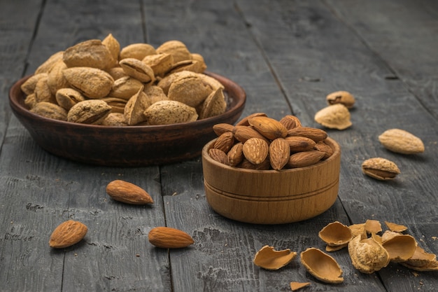 Peeled almonds, shells and unpeeled almonds on a wooden table