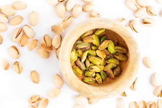 Peeled pistachios in mortar on a white.