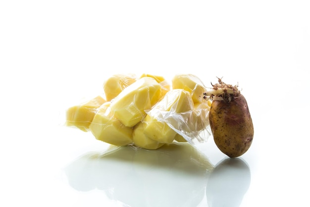 peeled potatoes closed in a vacuum bag and old sprouted potatoes on a white background