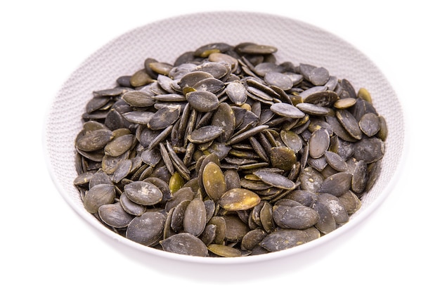 Peeled pumpkin seeds in a white plate on a white background isolated items and products