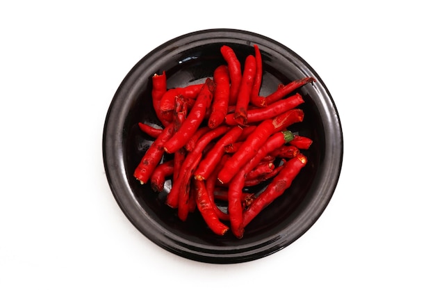 Peeled Red Chili on a black plate on a white background