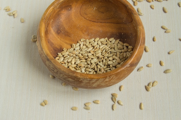 Peeled sunflower seeds in old wooden bowl on white cloth