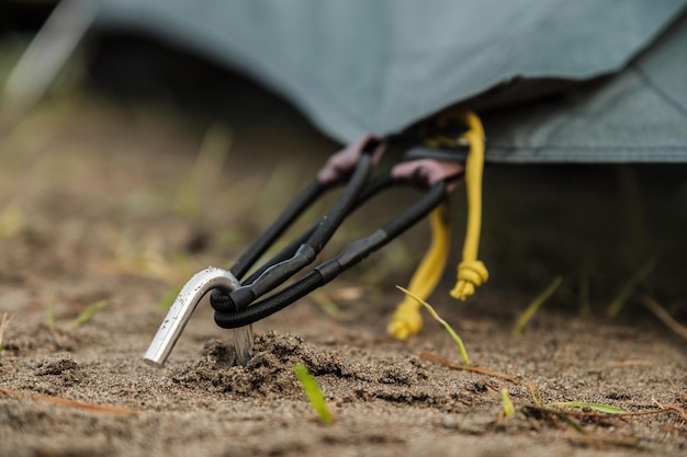 The peg from the tent is sticking out of the ground The tent is strapped to it