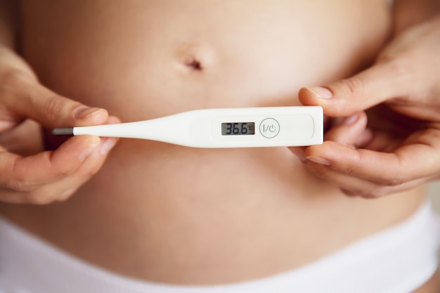 Pegnant woman with a thermometer in hands. Health during pregnancy. Close up