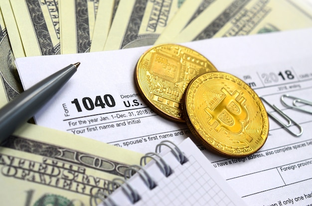 The pen, bitcoins and dollar bills is lies on the tax form 